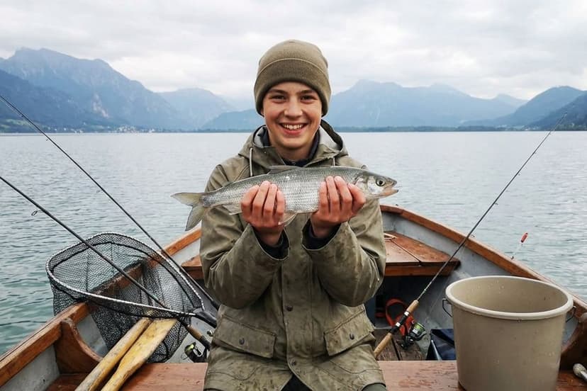 Angler fischt vom Boot mit Hegene auf Renken im Ammersee bei Morgenstimmung