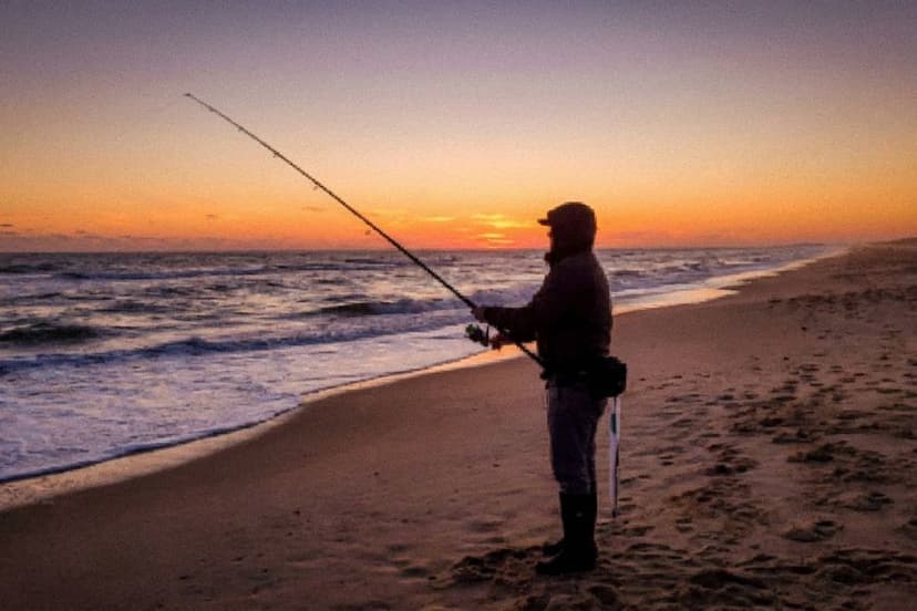Brandungsangler beim Auswerfen der Montage am Meeresstrand bei Sonnenuntergang