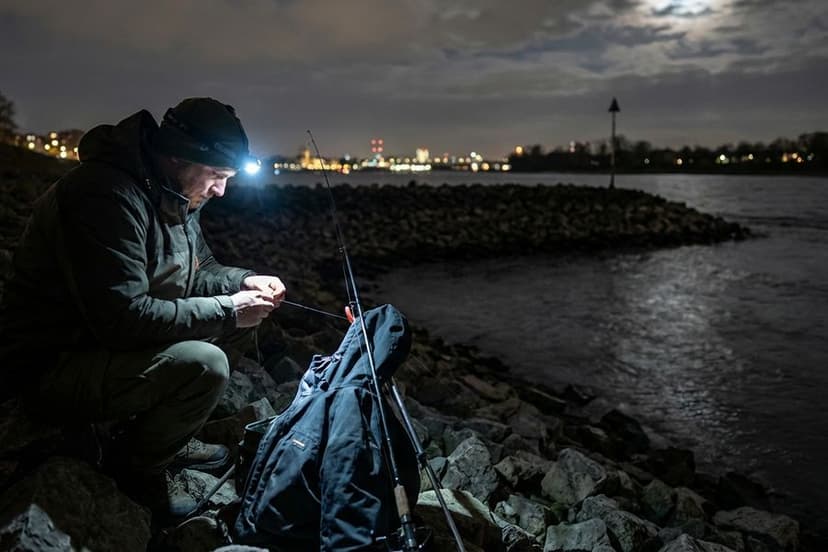 Aalangler am Rhein nachts mit Kopflampe an einer Steinpackung bei Buhnenfeld